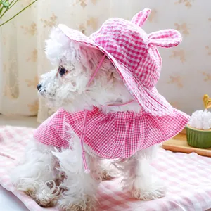 Detail of pink plaid pet sun hat with cute ears and matching cape on a small white dog