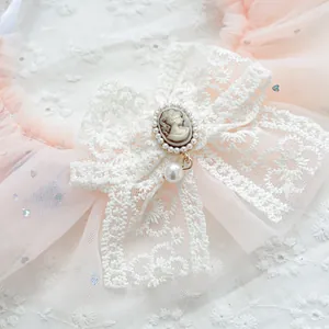 Detail of pink lace pet bib with vintage cameo, white pearls, and a large pendant drop