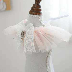 Close-up of pink layered mesh pet bib with white lace bow and vintage cameo pendant