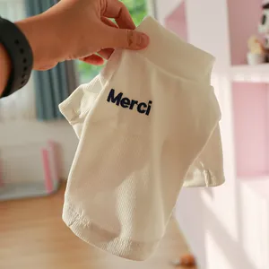 Detail of soft ribbed cream pet turtleneck featuring blue Merci embroidery