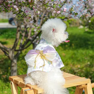 Detail of floral pet kimono featuring a large bow and golden knot on a white dog