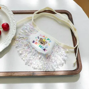 White pet birthday bandana with rainbow embroidery and soft tassels on a wooden tray