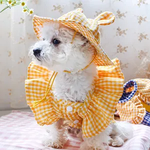 Close-up of a white dog wearing a yellow plaid bunny ear hat and matching ruffled outfit