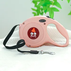 Laisse rétractable rose pour chien avec motif monstre et poignée ergonomique sur tapis