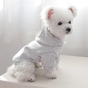 Side view of a white puppy wearing a light grey cotton hooded sweatshirt with cuffs