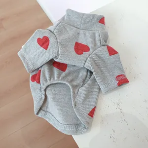 Close-up of gray pet shirt with red heart patterns and ribbed knit texture details