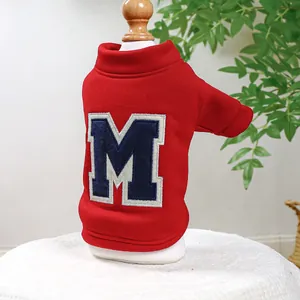 Detail of red warm pet hoodie with embroidered letter M on soft cotton fleece fabric