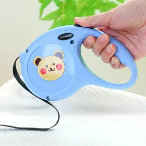 Gros plan d'une laisse rétractable bleue avec motif d'ours tenue à la main