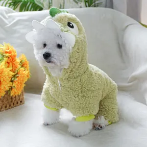Detail of a small white dog in a warm green dinosaur hoodie on a cozy sofa