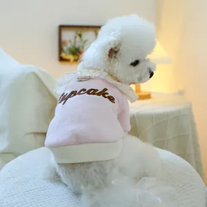 Pink dog sweater with white ruffle collar and Cupcake embroidery on a white poodle
