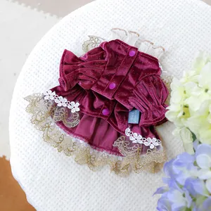 Detail of burgundy velvet pet dress with white lace trim and gold mesh layers