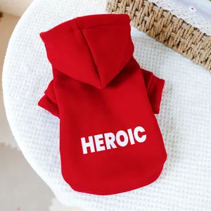 Close-up of red dog hoodie with white HEROIC print on a textured white background