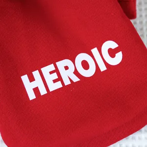 Detail of red knit pet hoodie with white HEROIC bold print text and soft fabric texture