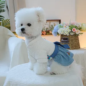 Dettaglio vestito per animali con ricamo floreale e fiocco in denim su maglia a nido d'ape