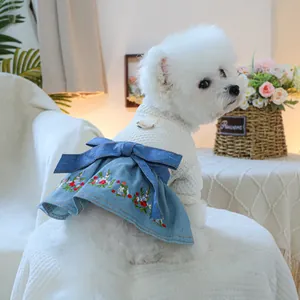 Detail of dog dress with white textured top, floral denim skirt and blue bow