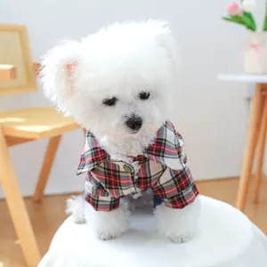 Close-up of a small dog wearing a red and green plaid shirt with button details