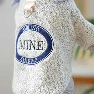 Detail of dog sweater showing embroidered patch and integrated D-ring leash attachment