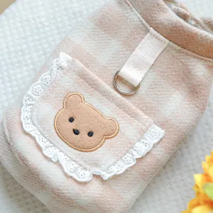 Nahaufnahme der rosa karierten Haustierkleidung mit Bärenstickerei und Spitzenbesatz