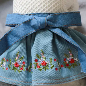 Dettaglio di un abito per animali in denim con ricami floreali e fiocco in vita decorativo