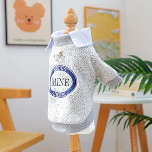 Detail of grey knitted pet sweater with blue striped shirt collar and embroidery patch