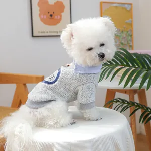 Detail of grey knitted pet sweater with blue striped collar and round crest badge