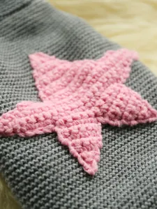 Detalle macro de jersey gris de punto para mascotas con estrella de mar de ganchillo