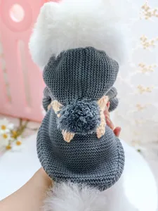 Detalle de jersey de punto gris para perro con capucha y pompón en un perro blanco suave