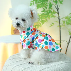 Detail van kleurrijk polkadot hondenshirt met D-ring gedragen door witte Bichon