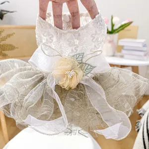 Detail of elegant white lace pet dress with floral embroidery and golden organza layers