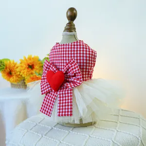 Detail of red and white plaid pet dress featuring a large bow and plush heart ornament