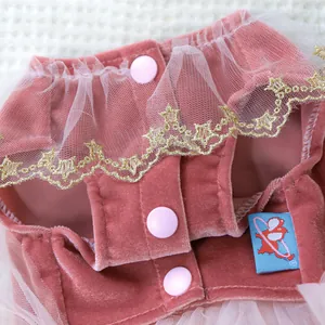 Detail of pink velvet pet dress with gold star lace and snap buttons