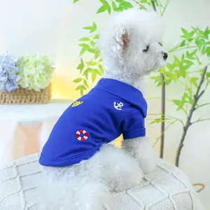 Détail du polo bleu pour chien avec broderie nautique porté par un chien blanc