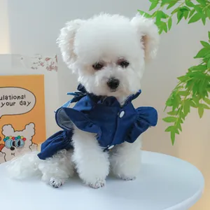 Détail de robe en jean pour chien avec col à volants et nœud sur une table blanche