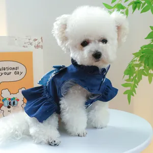 Détails d'une robe en jean pour chien bleu foncé avec volants et nœud portés par un Bichon