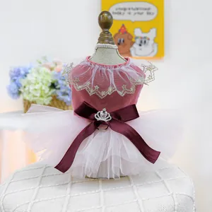 Detail of pink velvet pet dress with white lace collar and a red bow with crown rhinestone