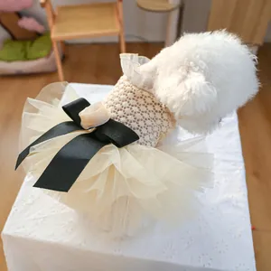 Detail of pet dress featuring beige lace top, layered tulle skirt, and large black bow