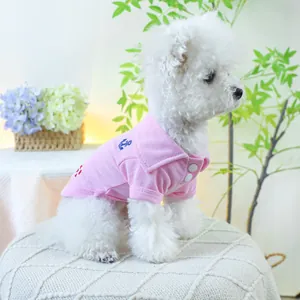 Polo rose pour animaux avec broderie ancre bleue et boutons blancs sur un chien bichon