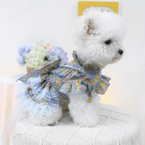 Detail of blue floral pet dress with pearl collar and layered lace hem on a white dog