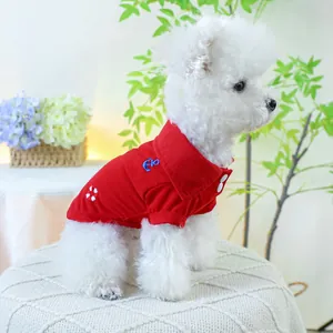 Détail du polo rouge pour chien avec broderie ancre bleue sur un caniche blanc