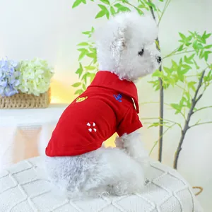 Détail du polo rouge pour chien avec broderie porté par un petit chien blanc au jardin