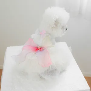 Detail of a white lace pet wedding dress with a large pink bow and heart pearl charm