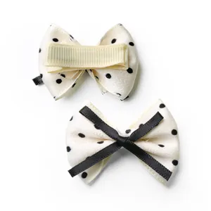 Detailed front and back view of a polka dot bow hair clip with a yellow alligator grip