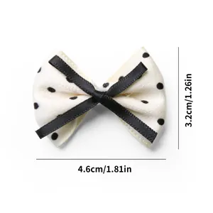 Detail view of a cream polka dot bow hair clip with size measurements 4.6cm x 3.2cm