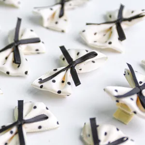 Close-up of cute polka dot bow hair clips with ivory fabric and black satin details