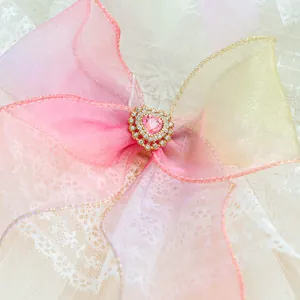 Detail shot of a gradient organza bow with a pink heart-shaped gemstone and gold trim