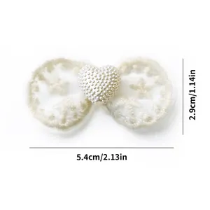 Detailed view of cream bow pet hair clip with star embroidery and heart pearl bead