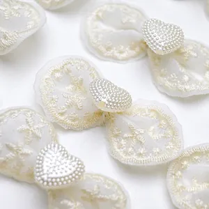 Macro detail of cream lace bow accessories with heart-shaped pearl bead accents