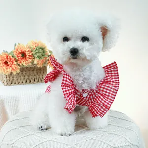 Détail d'une robe pour chien à carreaux rouges avec volants sur un petit Bichon