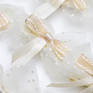 Close-up of cute pet hair bow with cream ribbon, gold stitching and polka dot mesh detail