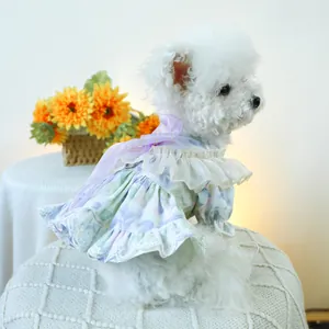 Floral pet summer dress featuring white lace ruffles and a cute purple bow on a small dog
